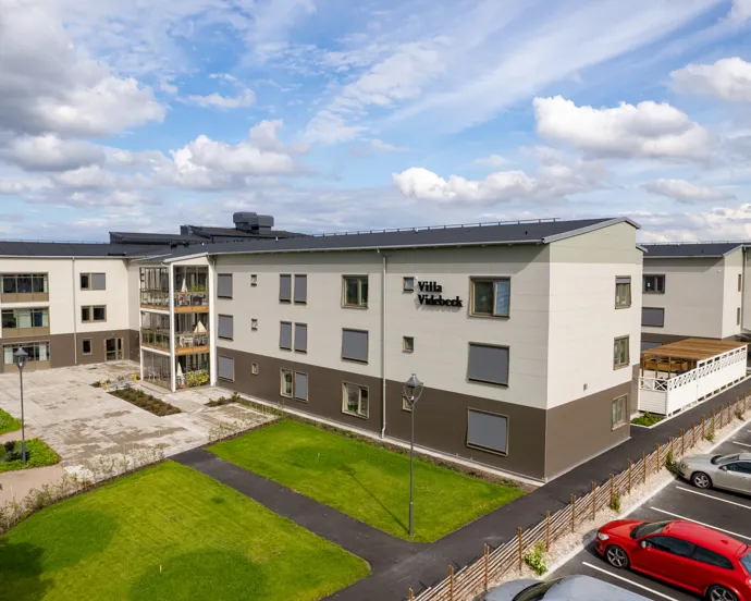 En grupp bilar som står parkerade på en parkeringsplats bredvid en byggnad.